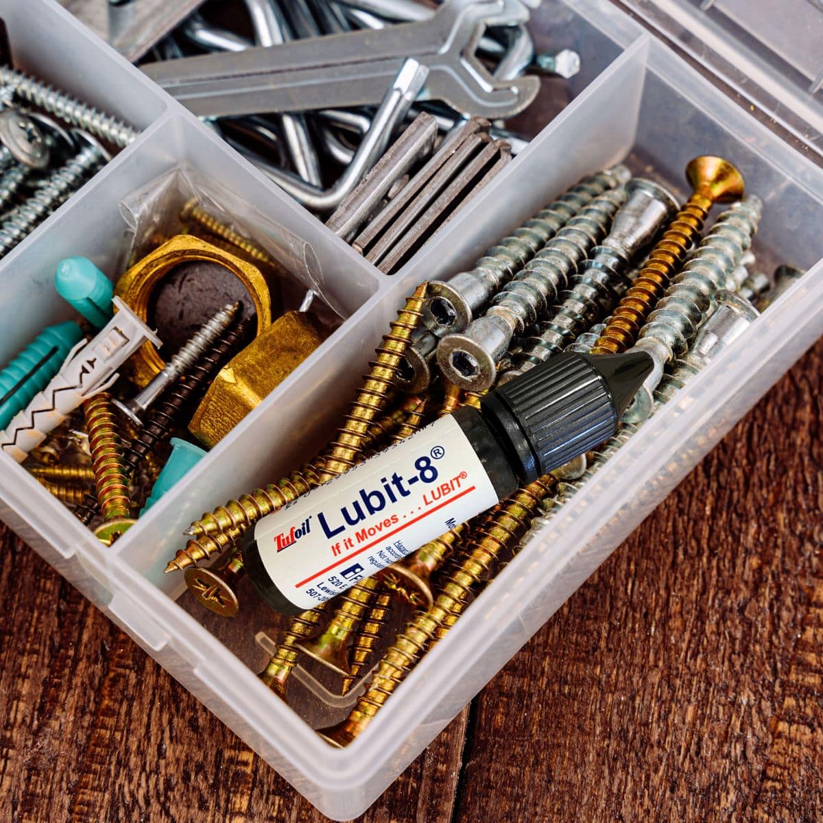 Lubricant bottle among screws and tools in a toolbox.